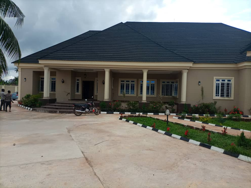 Completed cream bungalow with a dark pitched roof, landscaped gardens and paved forecourt